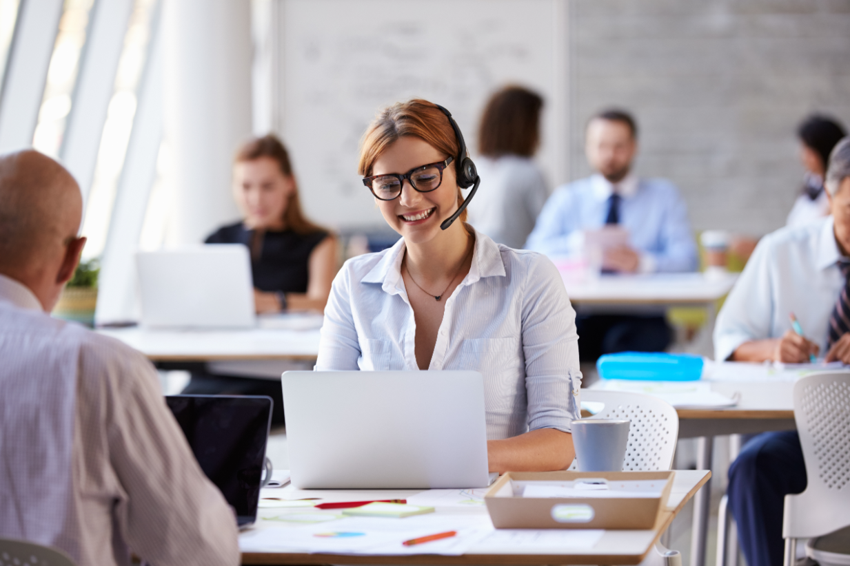 A customer service rep at her desk, on the phone with a customer.