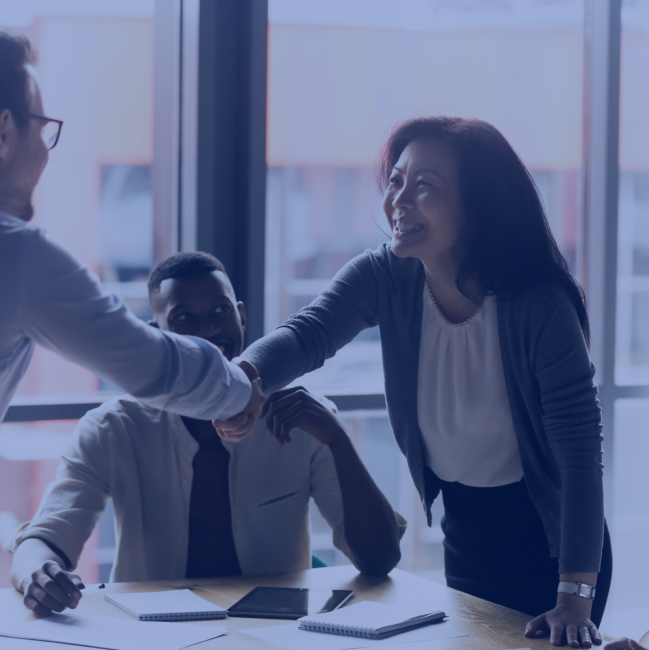 Asian American woman shakes hands with a man, closing a business deal or partnership.