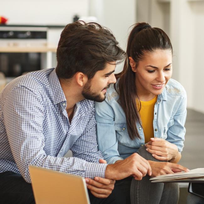 A couple buying a house reviewing docs with their realtor. 