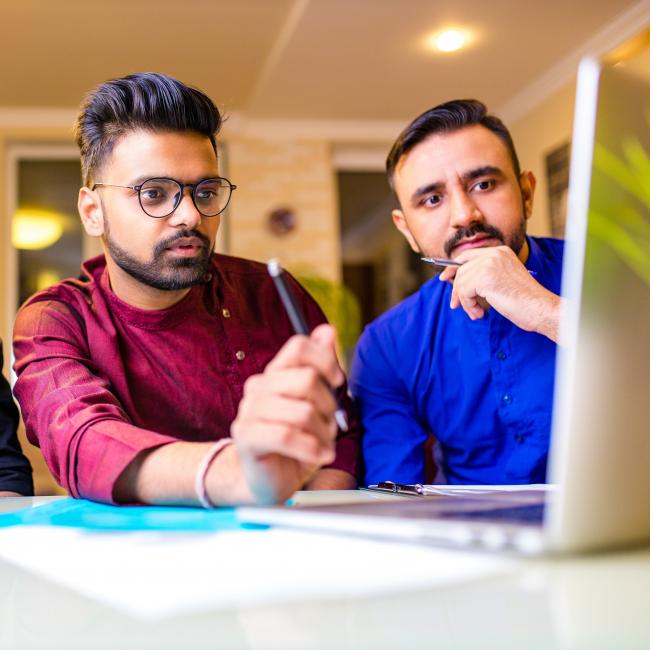 Three bank employees looking at a laptop screen, undergoing training.