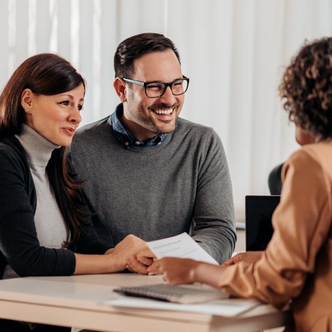 A couple sit at a desk, opposite a financial advisor