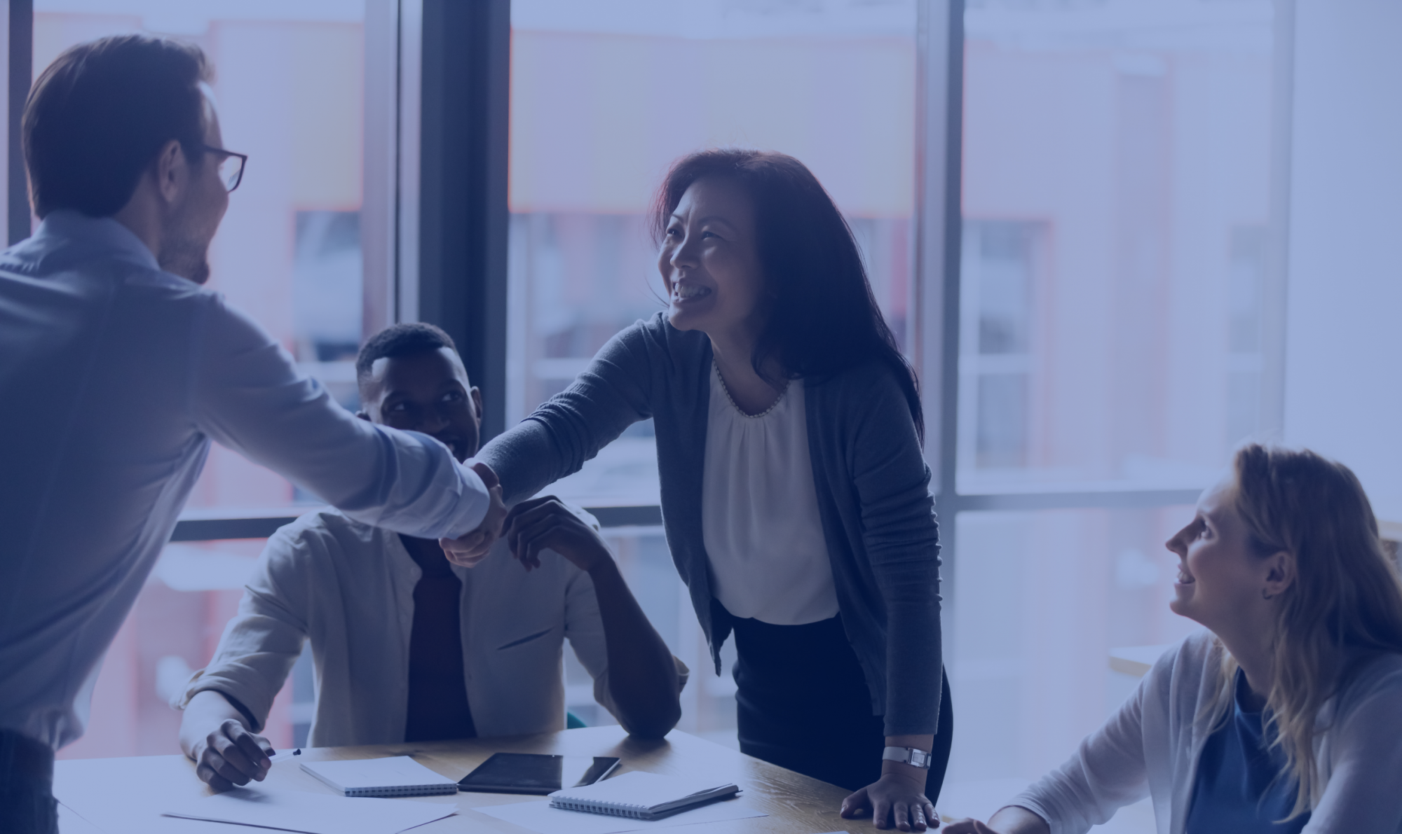 Asian American woman shakes hands with a man, closing a business deal or partnership.