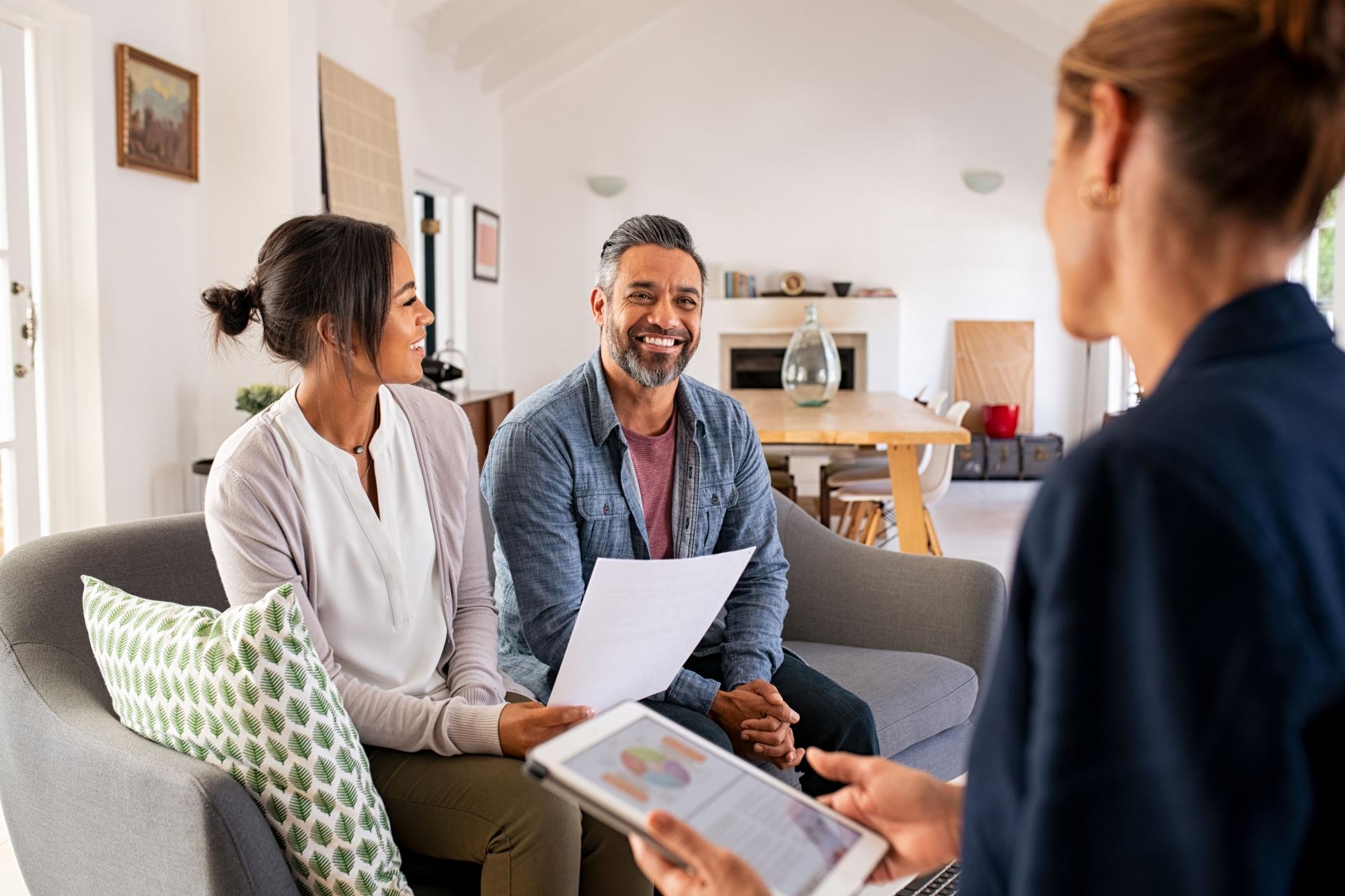 Hispanic couple smiling and sitting opposite a banker