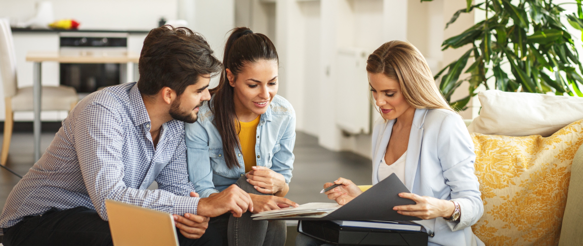 A couple buying a house reviewing docs with their realtor.