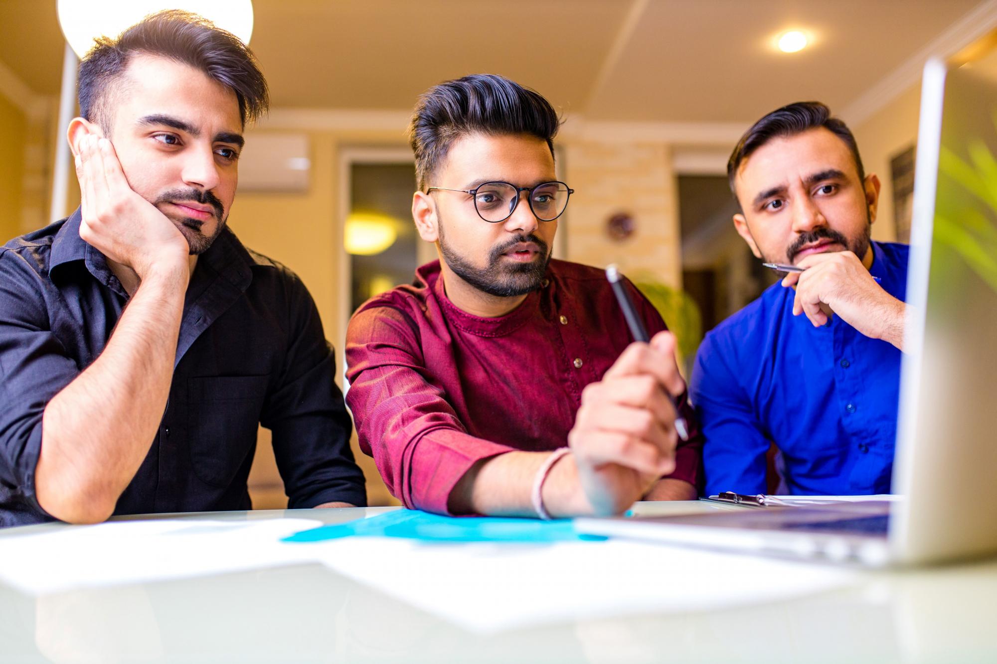 Three bank employees looking at a laptop screen, undergoing training.