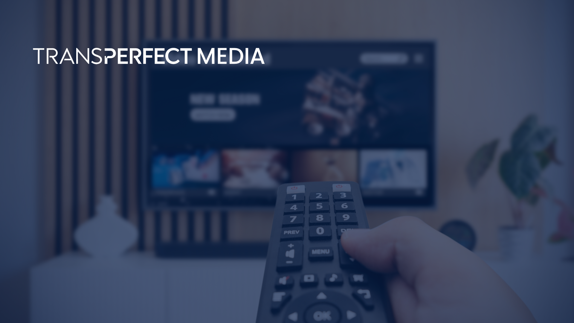 A hand holding a TV remote control, pointing it at a TV that has a streaming platform on it.