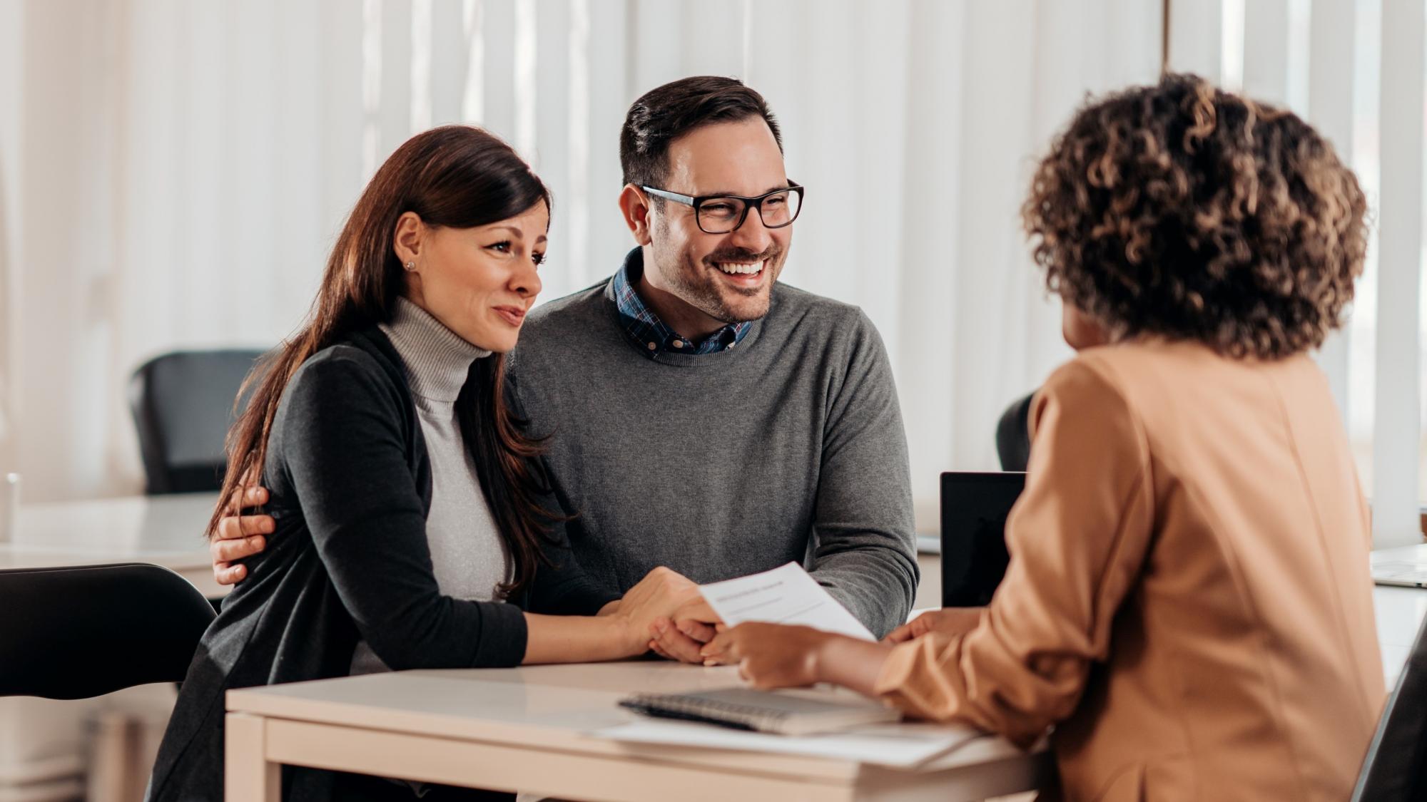 A couple sit at a desk, opposite a financial advisor